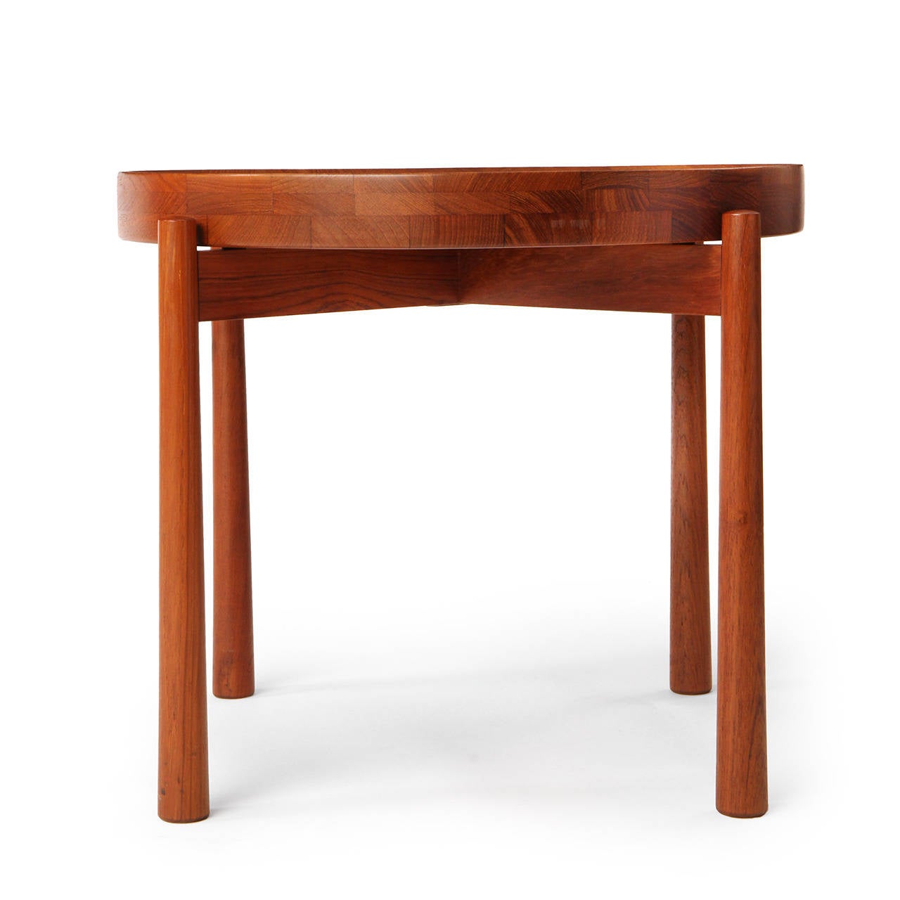A Scandinavian Modern tray table by Jens Quistgaard in solid teak. The table is finely crafted and has a removable and reversible lathe-turned top that is concave on one side and flat on the other, resting on an x-shaped stretcher and tapered dowel