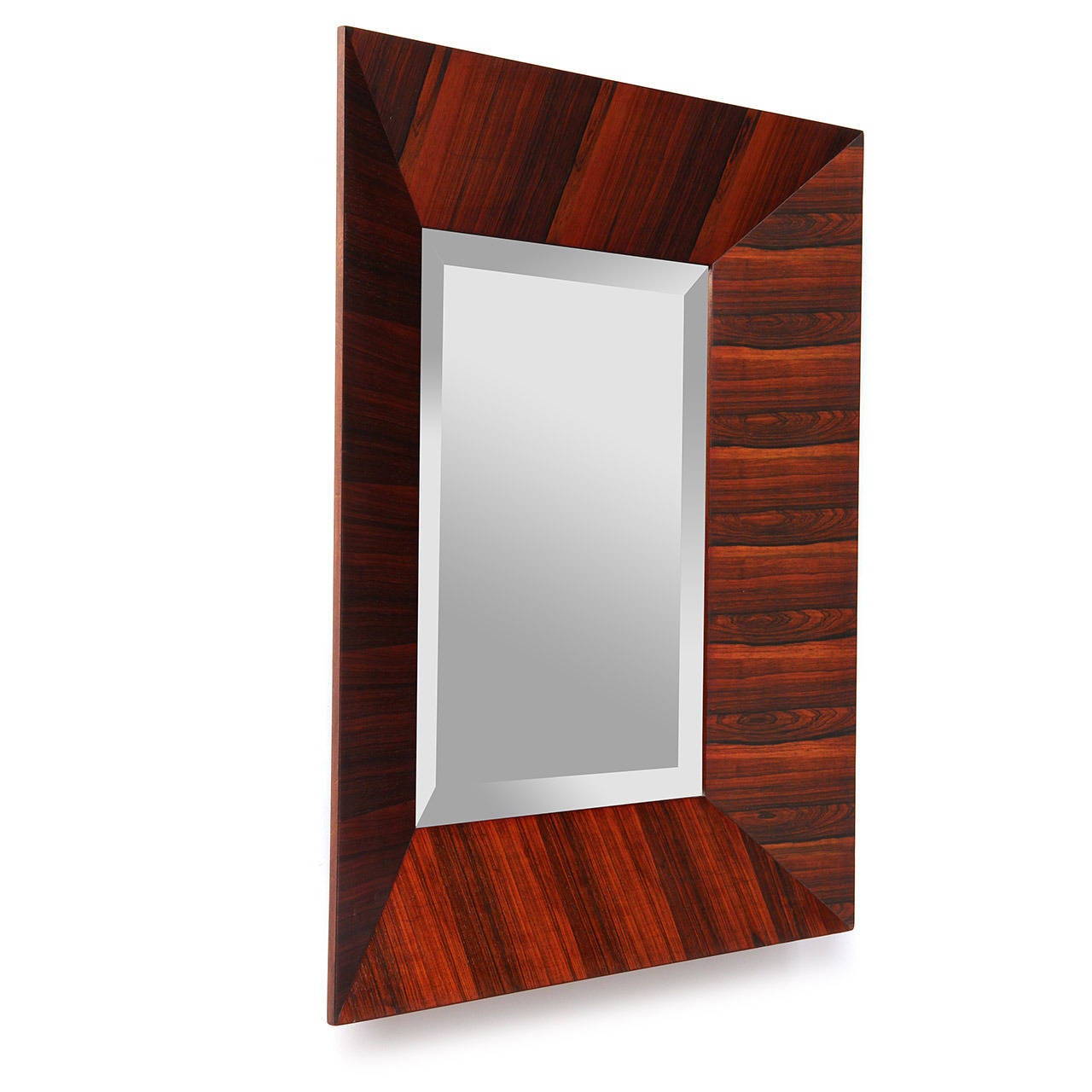 A scarce and expressive rectangular beveled glass wall mirror crafted of highly figured Brazilian rosewood having a beveled, projecting frame with diagonal joinery.