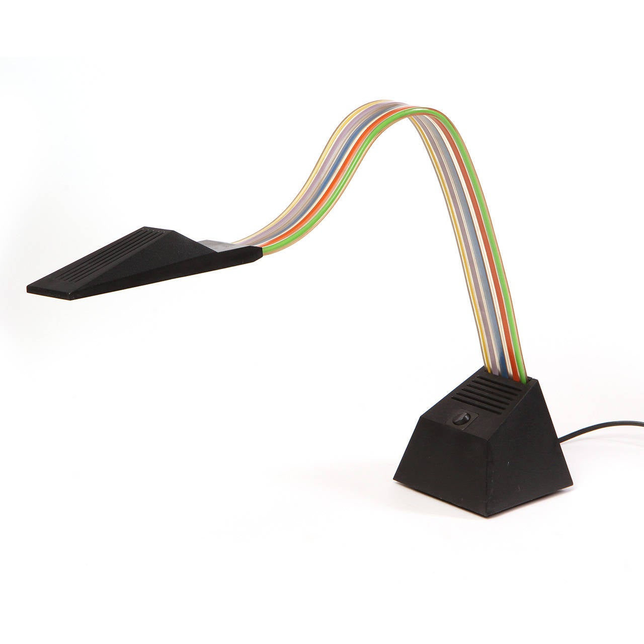 A sculptural, dramatic and unusual adjustable Nastro desk lamp having a flexible multicolored extruded pvc stem with electrical cabling rising from a polycarbonate weighted base.