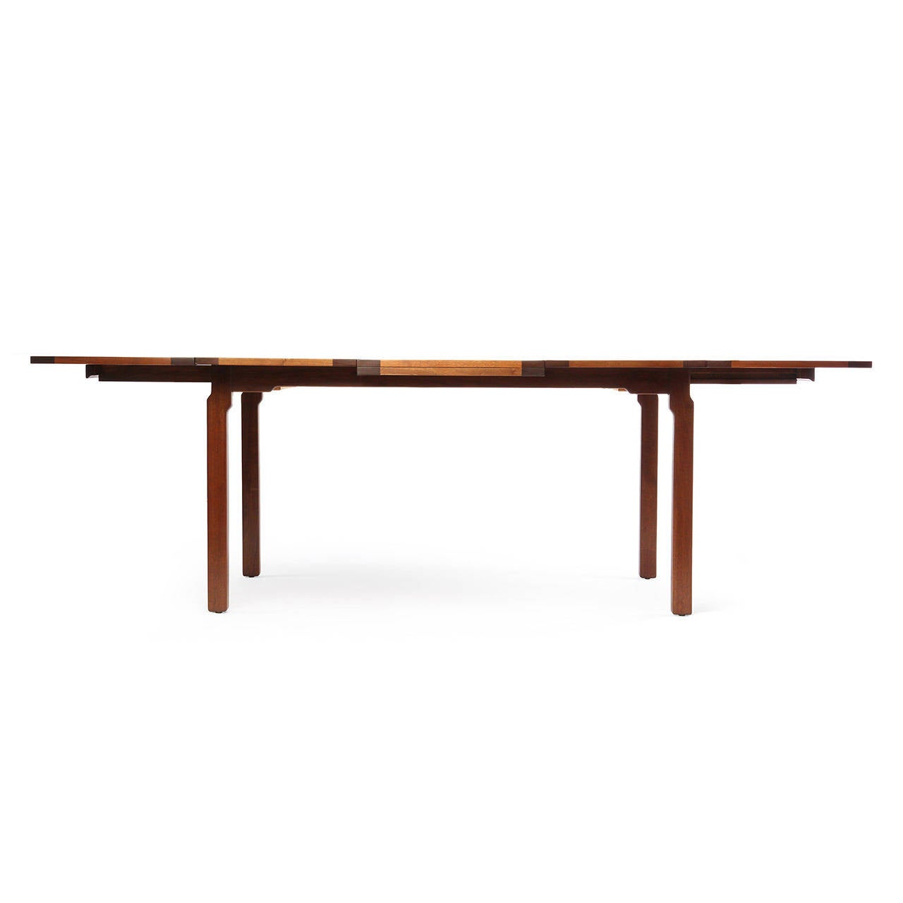A superbly detailed and impeccably crafted expandable Arts & Crafts-influenced dining table having a floating top fashioned of contrasting pegged planks of bleached and natural walnut resting on an exposed shaped walnut base.