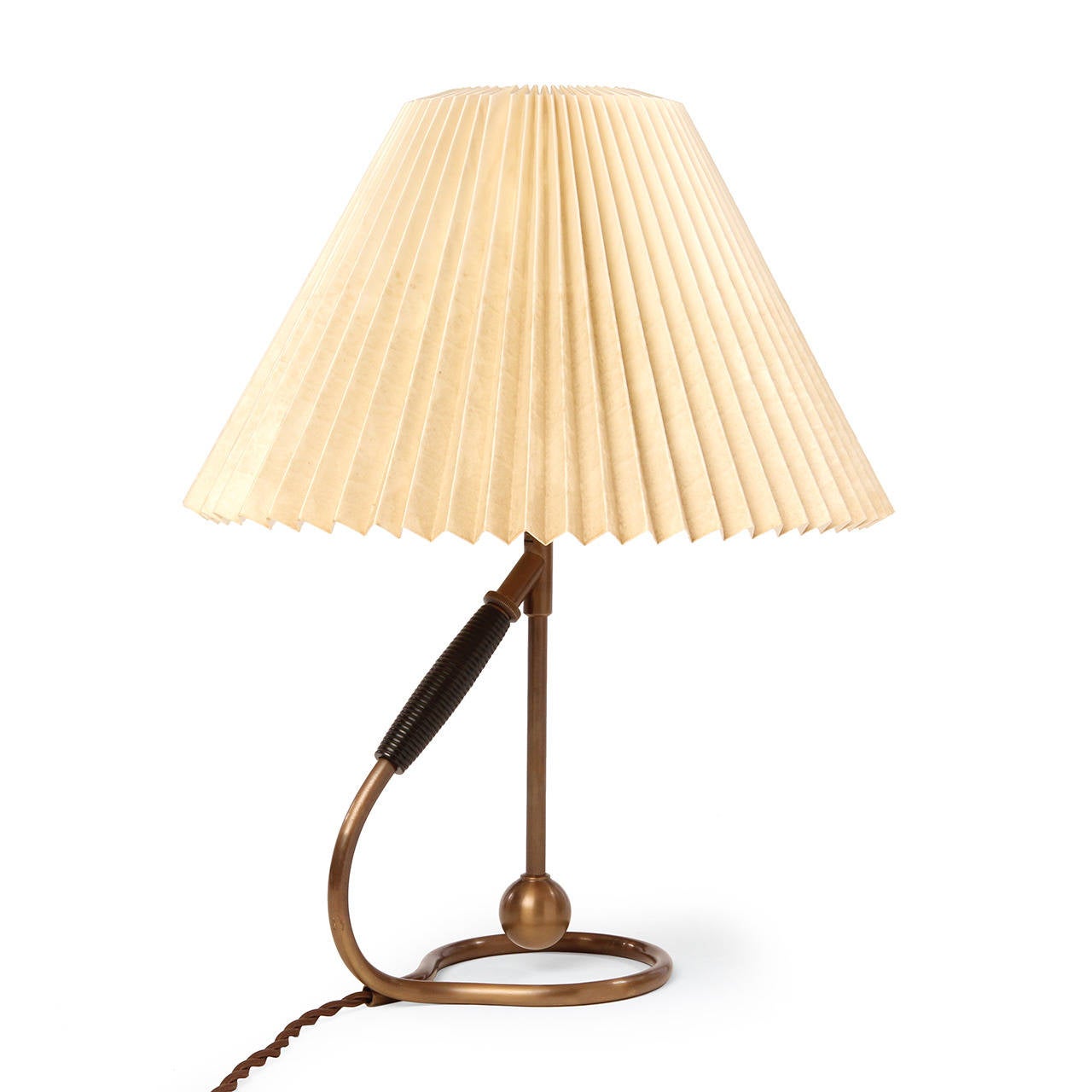 A sculptural, versatile and elegant lamp in warm lacquered brass with a pleated paper shade, having a rotating mechanism that enables different angles to be locked in place, allowing it to be used both as a table and wall-mounted lamp.