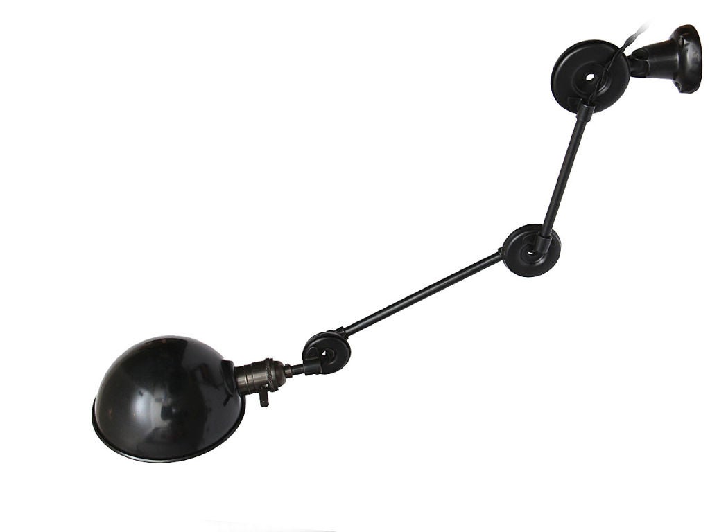 A patinated steel industrial wall lamp with infinitely adjustable arms, wall mount bracket and a steel shade.