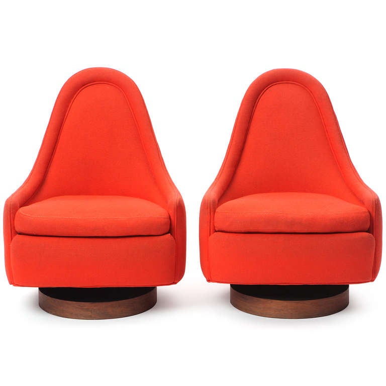 A pair of sculptural, fully upholstered and highly comfortable lounge chairs upholstered in a cardinal red wool fabric. Rising from a walnut disk base, these diminutive chairs have a high degree of mobility, tilting and swiveling with great ease.
