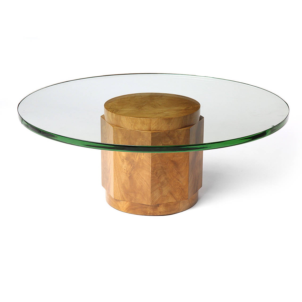 An elegant and sculptural low table having a burled faceted columnar wooden base supporting a thick round glass top.