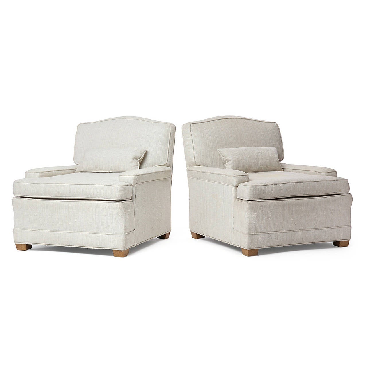 A finely crafted and generously scaled pair of scroll-top upholstered lounge chairs having sculptural bodies with distinctive shortened arms resting on squared pale walnut feet.