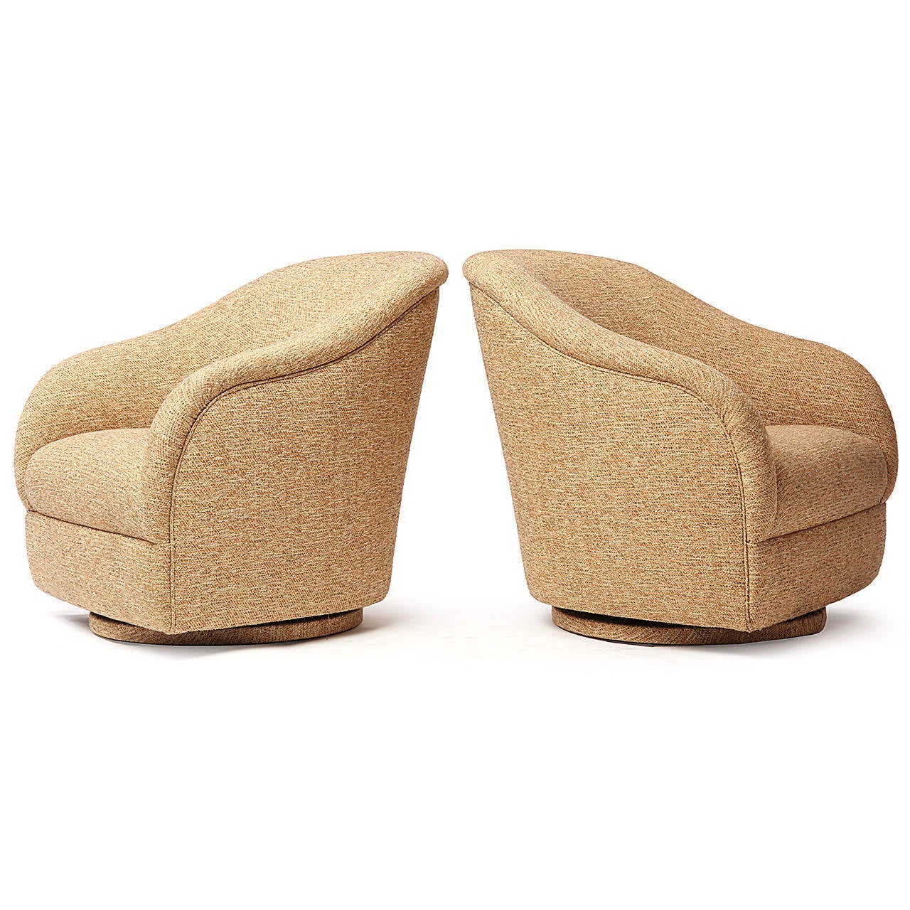 A sculptural and beautifully proportioned pair of swiveling lounge chairs on disc bases finely upholstered in an earth-toned textured bouclé.