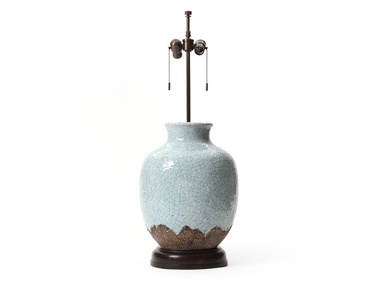 A ceramic table lamp with green-blue crackle drop glaze on an ebonized walnut pedestal base with new wiring and brass hardware.