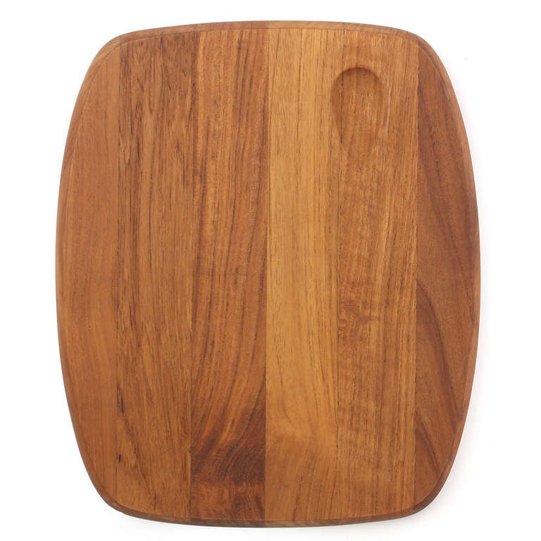 An elegant and sculptural cutting board and knife in teak and steel. 