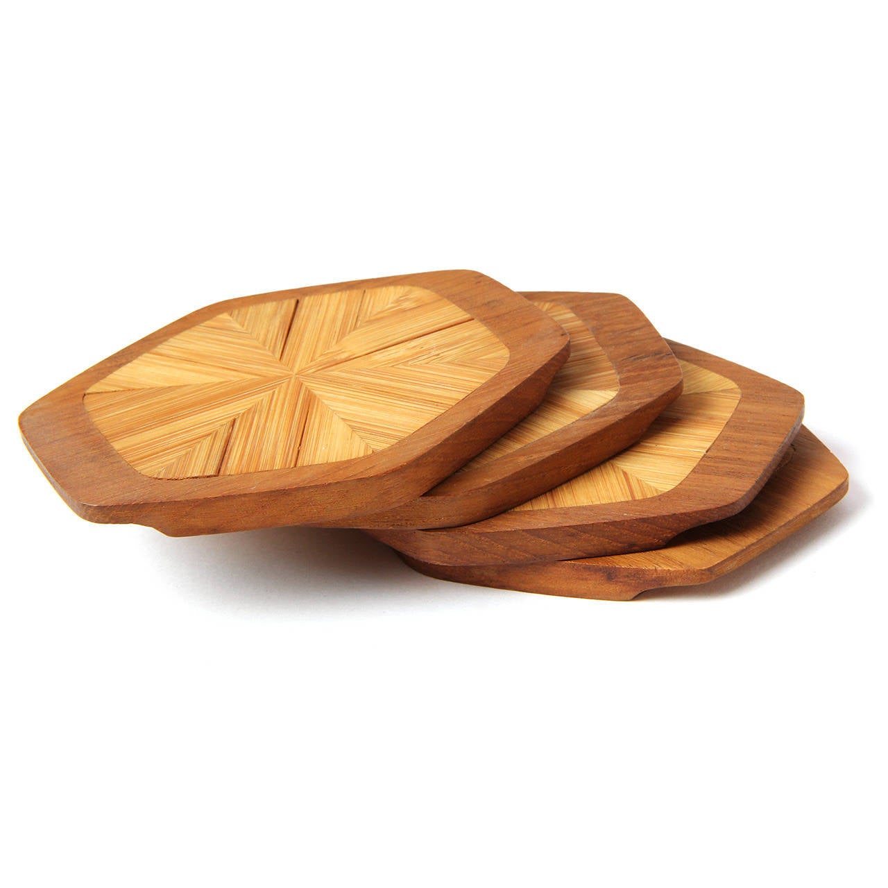 A group of finely crafted hexagonal teak coasters inlaid with split bamboo arranged in a sunburst pattern.