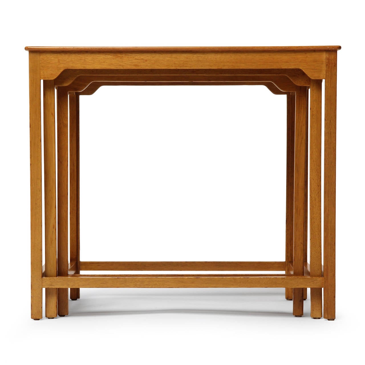 An elegantly detailed and finely crafted set of nesting tables in light walnut.
