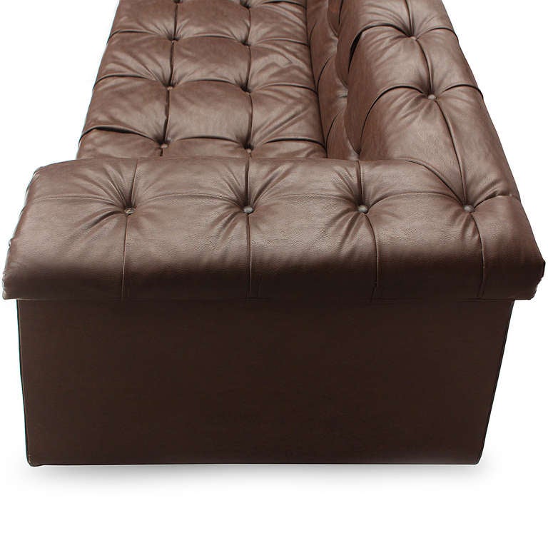 A generous and highly comfortable L-shaped sectional sofa on casters in button-tufted chocolate Naugahyde.