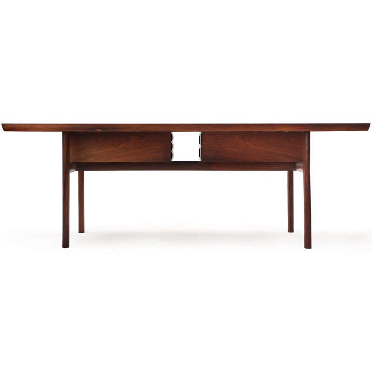 An exceptional, refined and rare metamorphic desk hand crafted in beautifully figured rosewood having exposed through tenon joinery and unusual and ingenious floating banks of drawers that can rotate ninety degrees inward so that the desk can