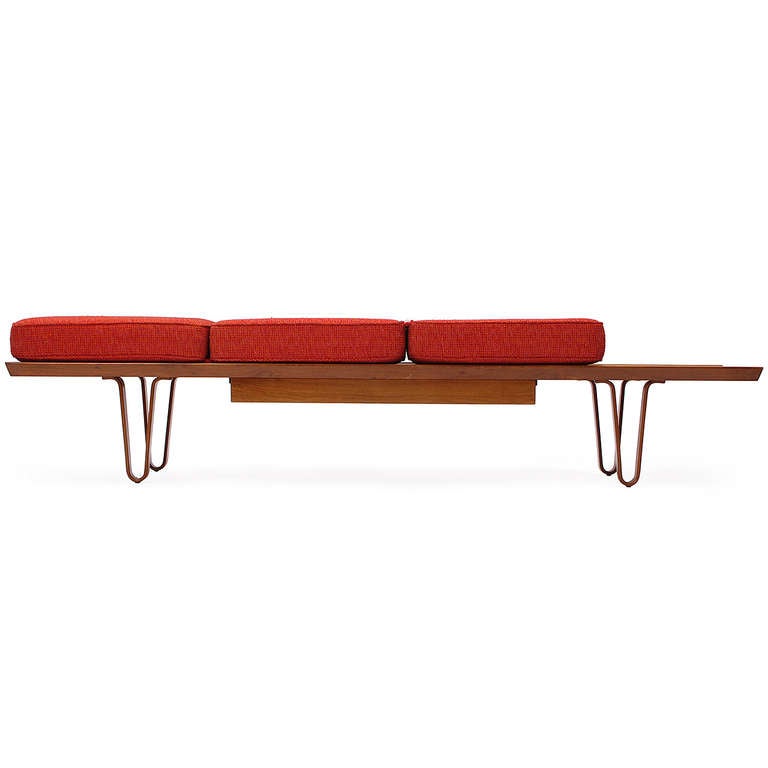 A good Long John bench in walnut with laminated wood hairpin turn legs and a floating central drawer that has hinged seating cushions upholstered in a rich red bouclé fabric.