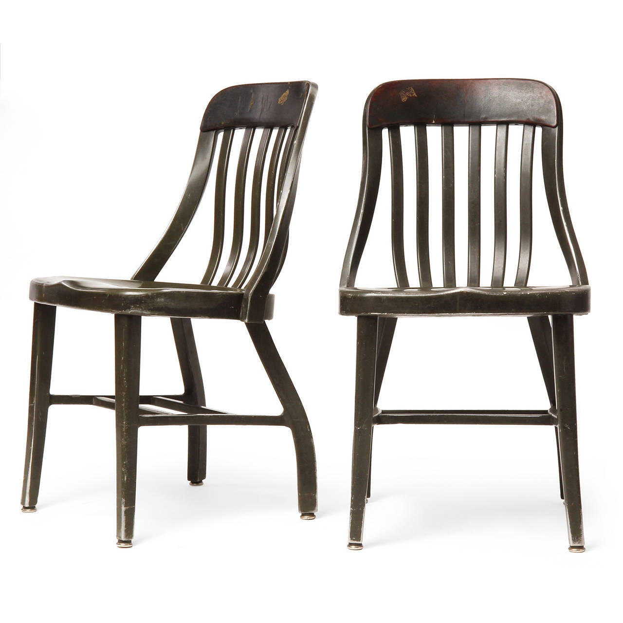 An expressive and unusual pair of side chairs made of cast and formed aluminum having scrolling slatted backs with a narrow leather cushion and dramatically angled rear legs.