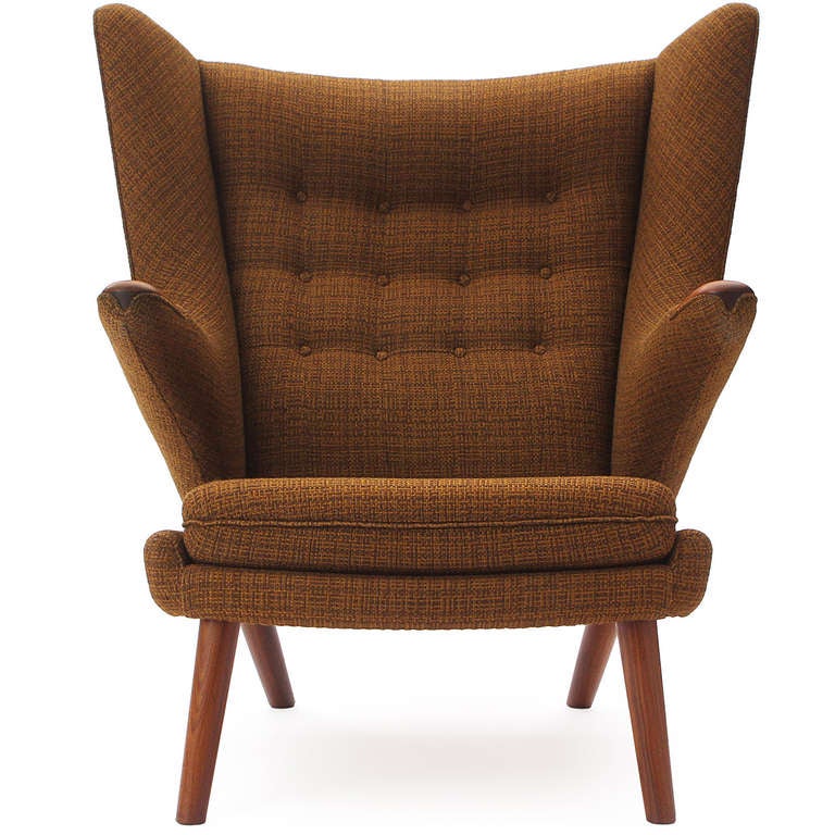 A stately and sculptural Papa Bear wing chair having cantilevered arms, tapered teak dowel legs; newly and beautifully upholstered in a soft and rich rust woven fabric.
