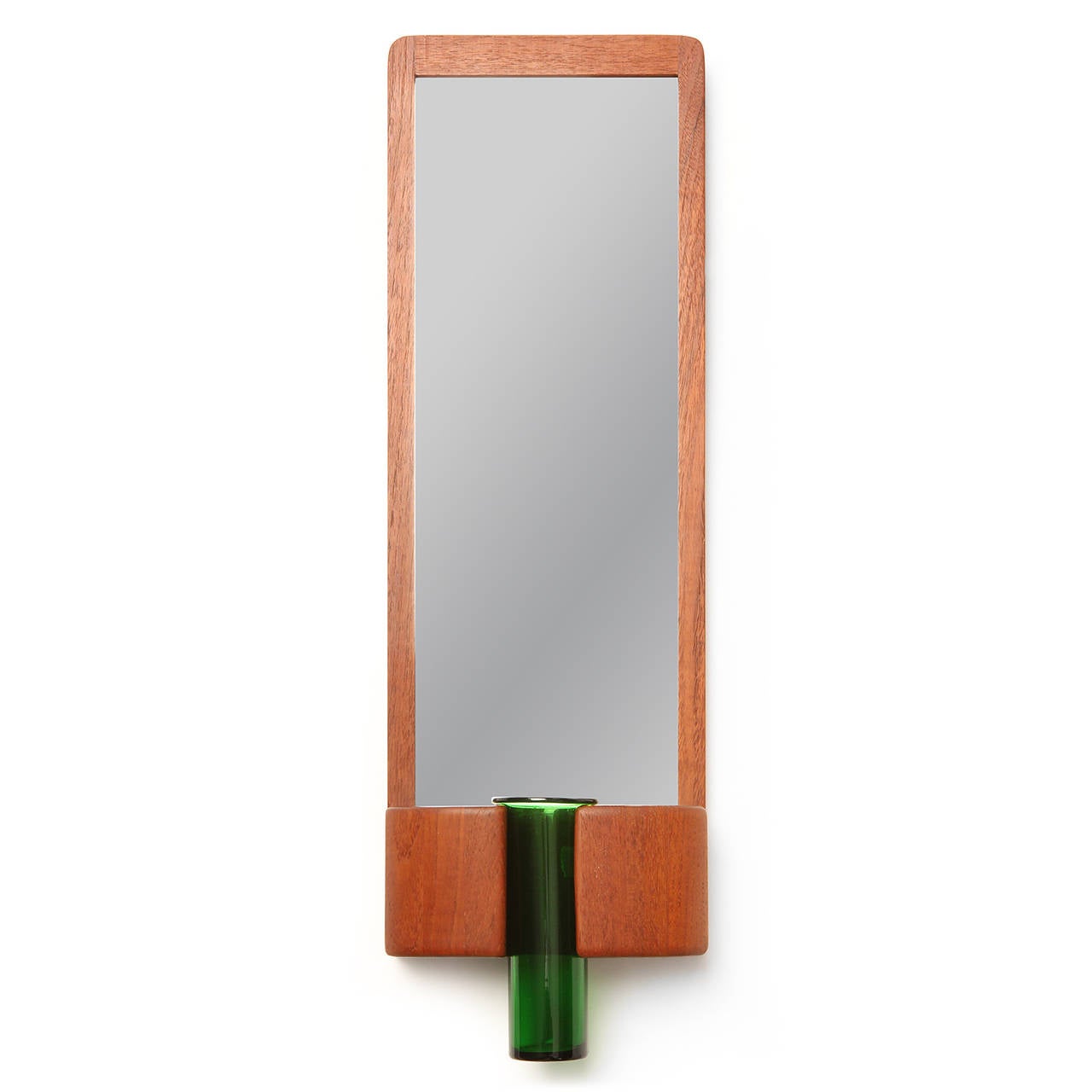 A spare and elegant teak mirror having a staved sculptural receptacle at the base holding a luminous and expressive green glass vase by Holmegaard.