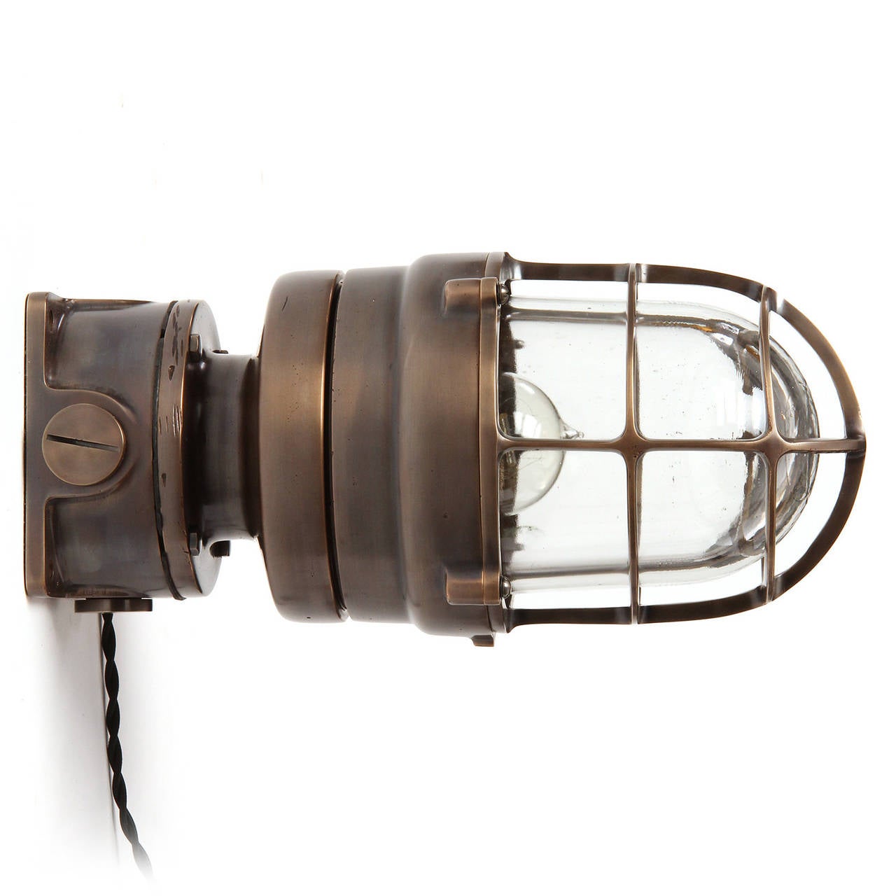 A substantial patinated and polished industrial bronze sconce of great quality, having a thick clear glass cage-encased light diffuser. This sconce can be wall or ceiling mounted, and also functions as a desktop light.