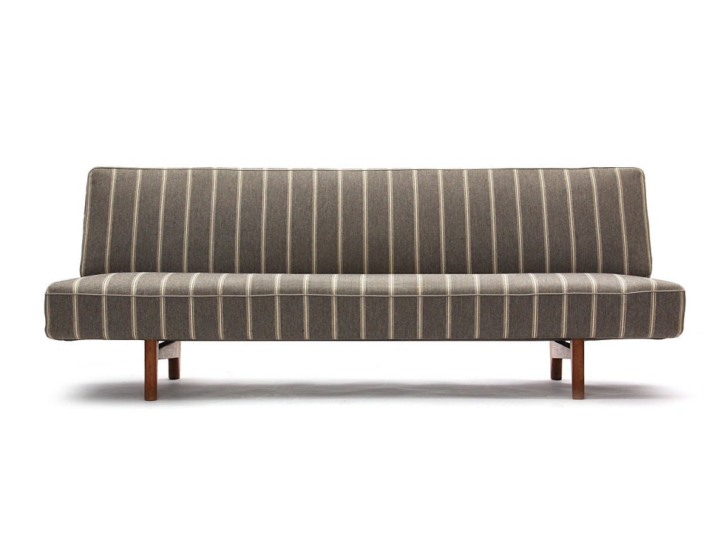 An armless sofa comprised of two cushions supported by two tappered dowl legs. Striped Danish wool upholstery. Cabinetmaker Johannes Hansen