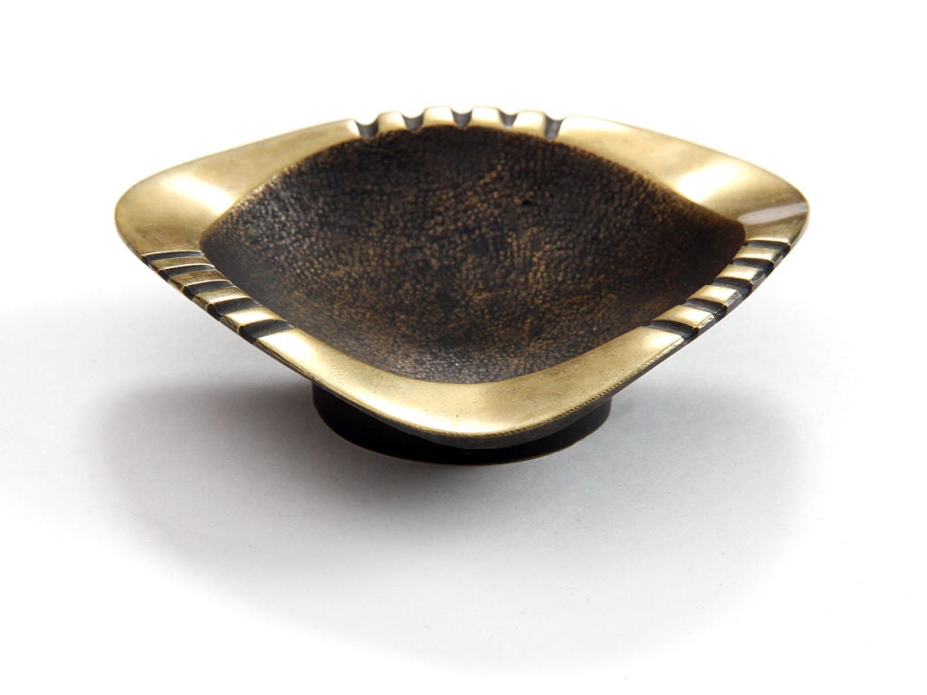 A patinated brass ashtray with scored edges