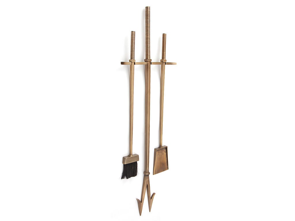 A set of three oversized wall mounted bronze fire tools, with broom, shovel and poker. 