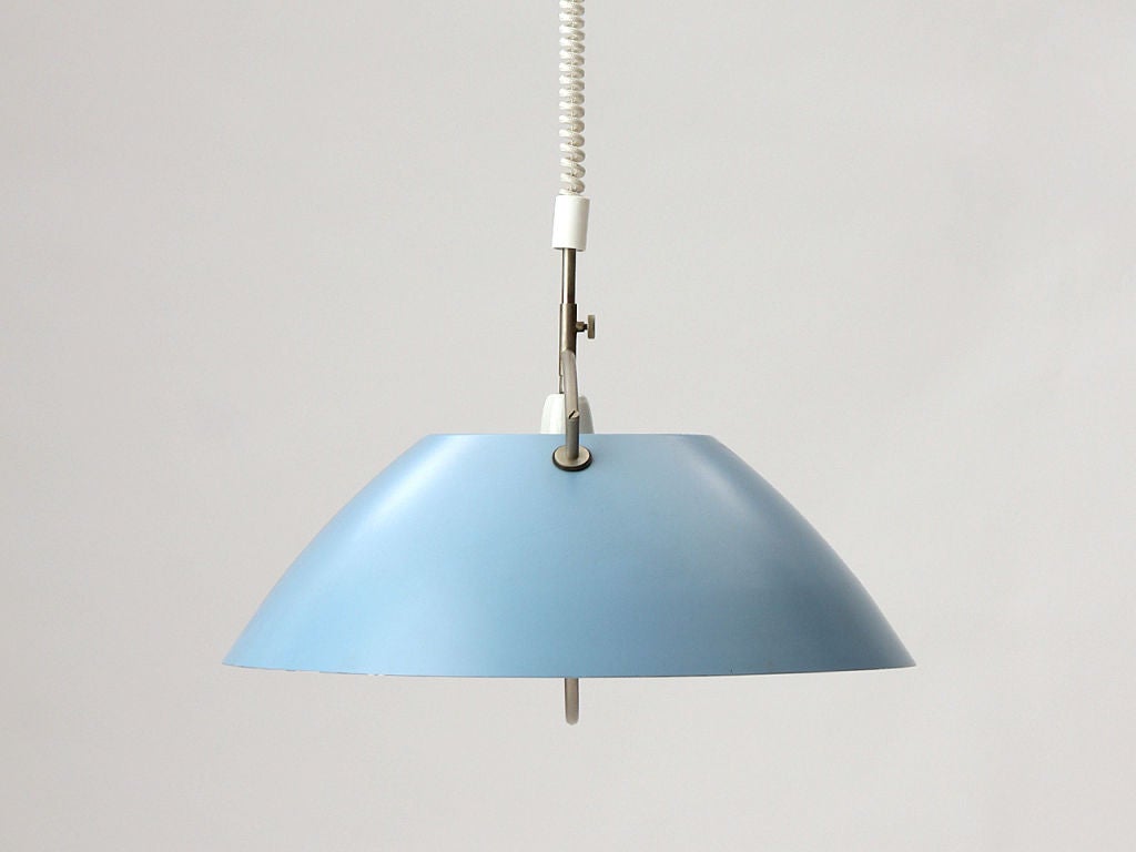 A pendant light with blue painted metal shade and center handle to allow user to adjust drop height via cable lift without having to touch the shade.