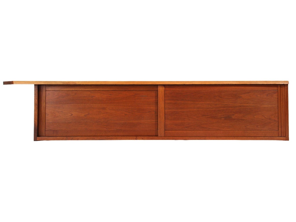 A walnut wall mount cabinet with two sliding doors concealing storage and an overhanging live edge top.