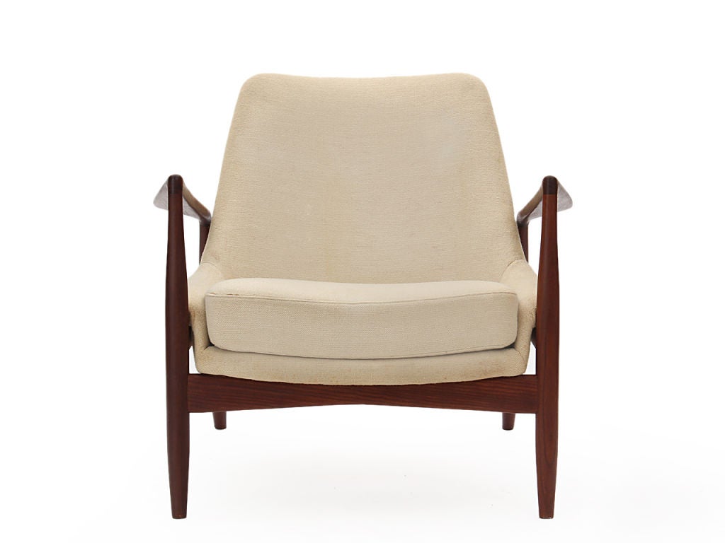 A pair of upholstered “seal” lounge chairs with exposed teak frames.