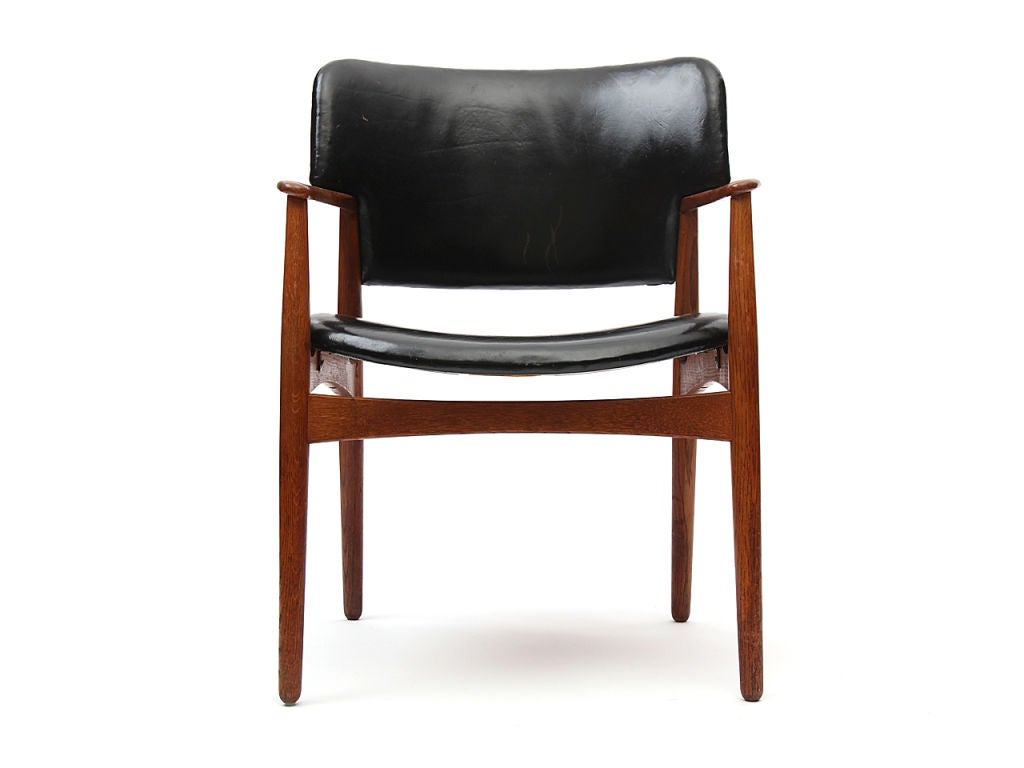 An oak armchair with the original black leather upholstery.