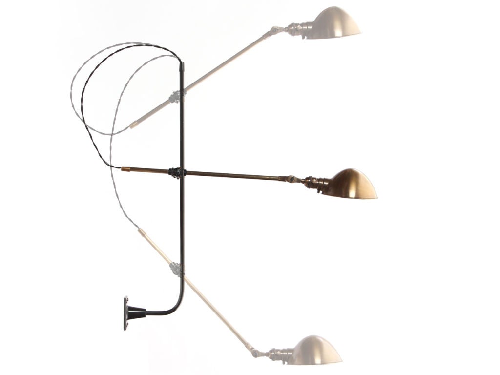 A wall light with a brass half-round dome on a curved-steel arm.