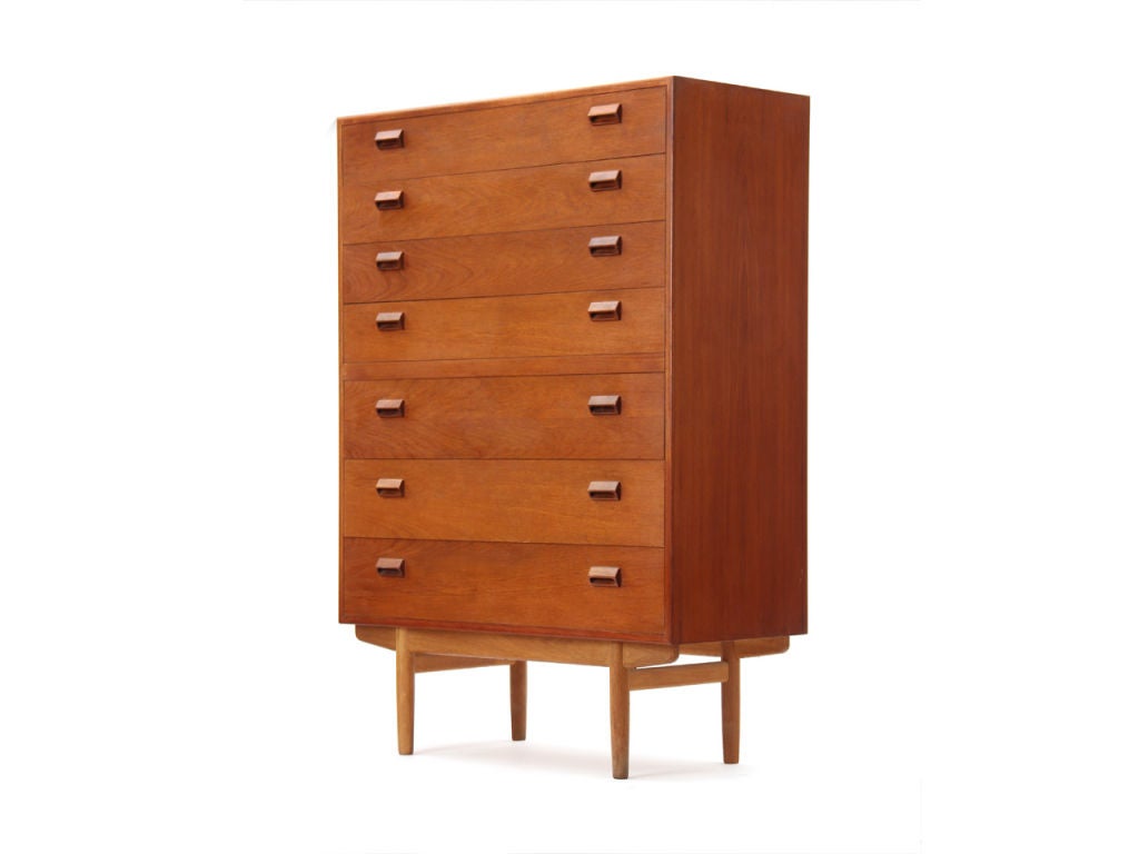 A tall seven (7) drawer dresser / chest of drawers designed by Borge Mogensen. Dresser is constructed of solid teak wood with integrated wood handles on an oak base with tapered dowel legs. Made in Denmark by Neils Vodder, circa 1960s. Two (2)