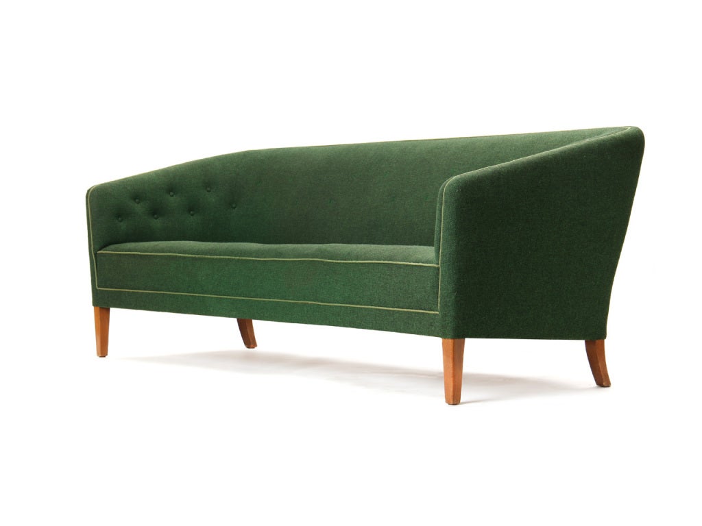 A cushion less sofa with high back and button tufting with teak legs.