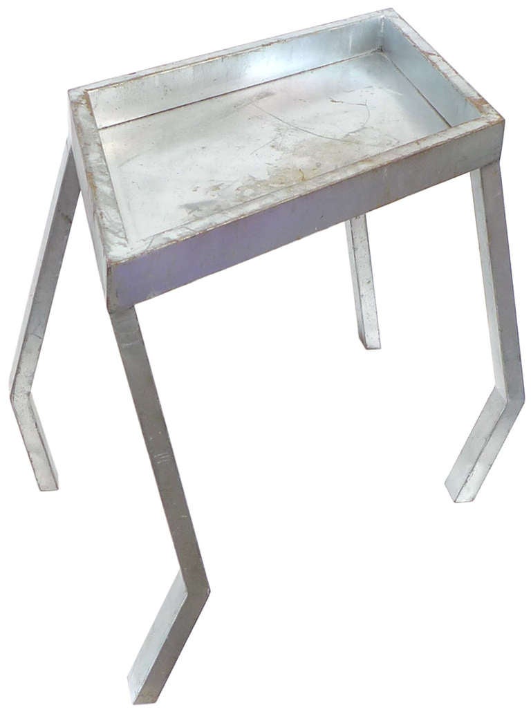 A custom, scratch-built side table in aluminum.  This unique piece evinces Memphis Milano inspiration with its wonderfully twisted, sculpturally-cubist form of an inset, rhomboid top and oddly-angular legs.  The table wears a nice patina likely from