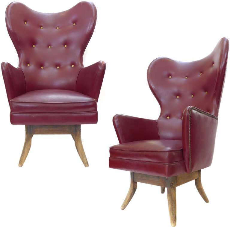 An amazing pair of wingback chairs with incredible form and style. These chairs originally lived in a Hollywood jazz club in the 1950's and they evoke the spirit of that time. Sexy, exaggerated wings and cutouts with fantastic brass stud and button