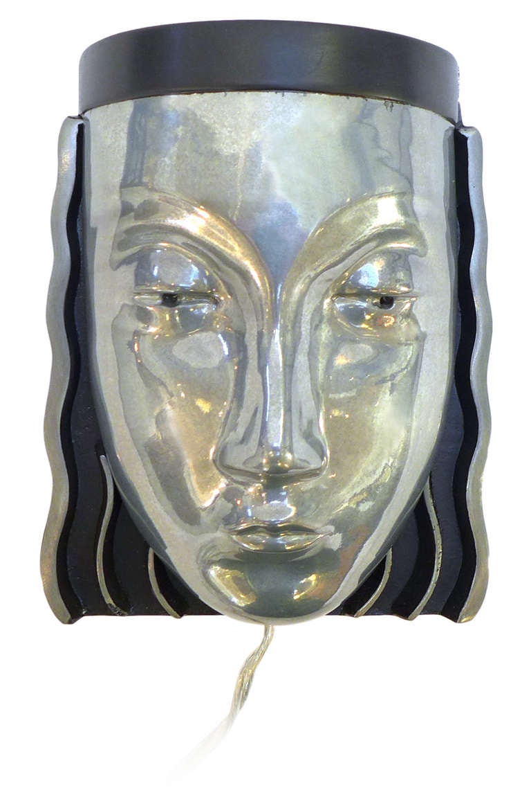 Extremely stylized and beautifully cast aluminum face sconces. Uplight and perforated eye illumination from internal fixture. Strong Art Deco lines and wonderful details. A very unusual and graphic lighting concept.