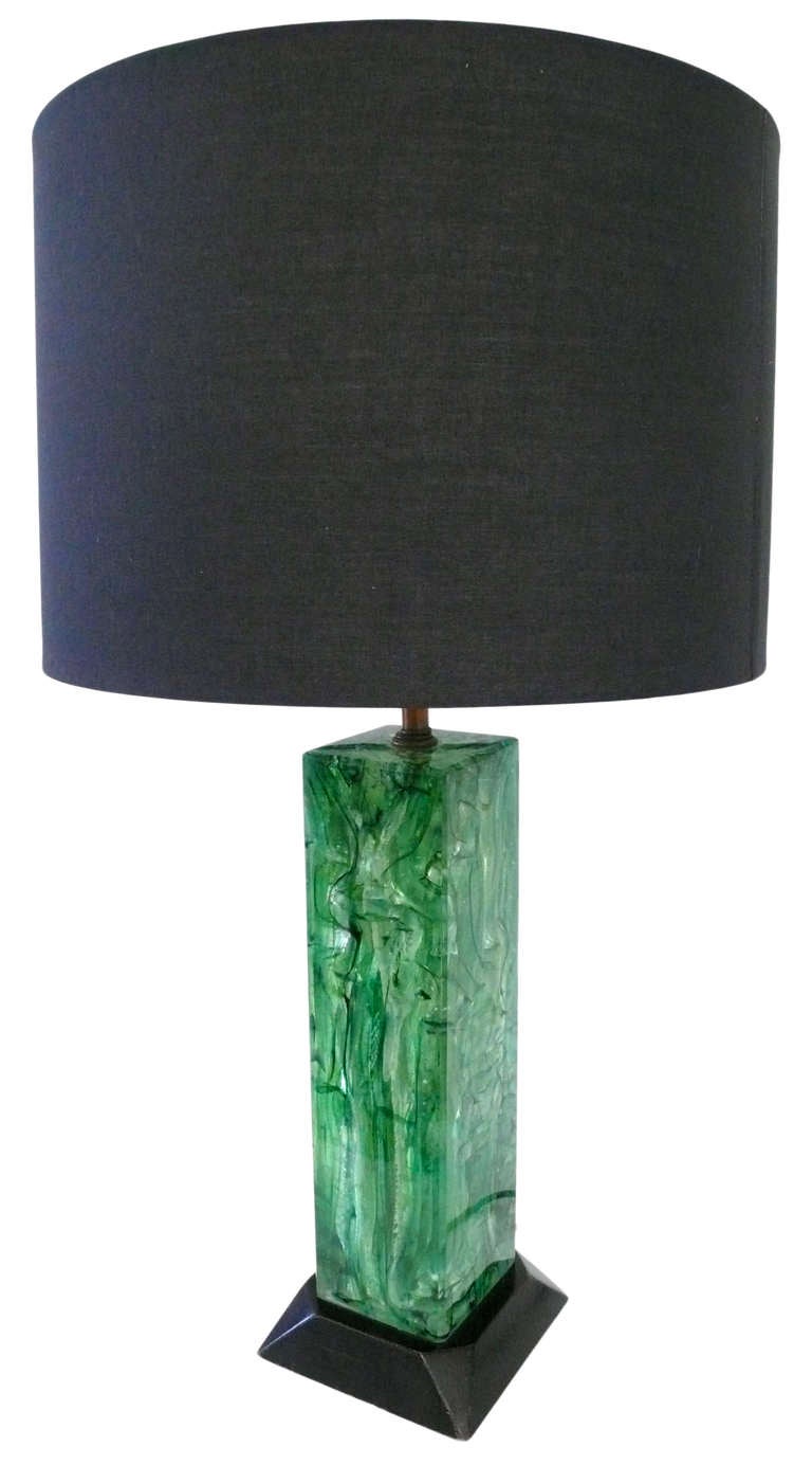 A wonderful and unusual green acrylic table lamp with beautiful internal striations and decorative inclusions. This monolithic form has subtly beveled edges and an original black lacquered, faceted base. A bold decorative statement. Original brass
