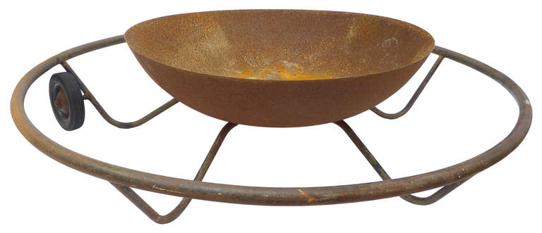 An unusual mid-century, welded-steel mobile fire pit.  Comprised of plate and tubular steel, this piece displays great design and character with its curvilinear leg structure and unique mobility supplied by two attached wheels.  Both sculptural and
