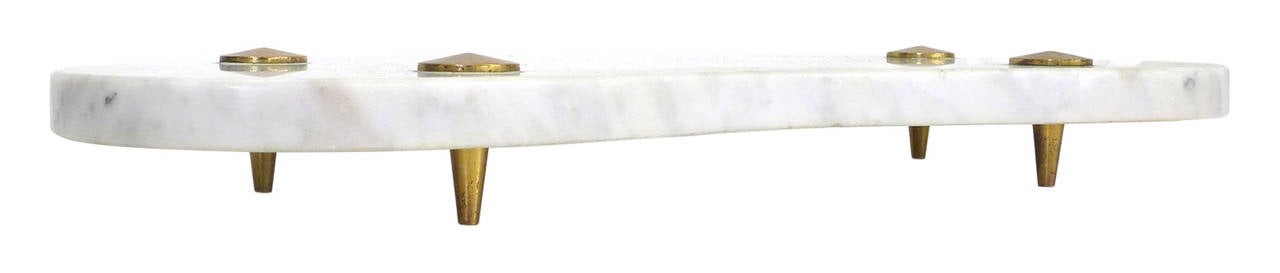 An elegant Italian tray of marble and brass.  Likely intended as a cheese-tray, a classic, mid-century, bulbous-boomerang marble-slab form sitting atop four delicately tapered brass legs held tight by pointed brass caps at the surface.