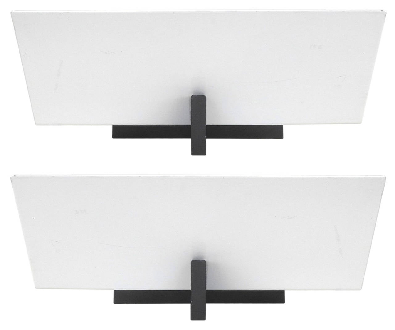 Graphic and geometric, an enameled white prism borne by a black, cantilevered wall-plate and arm, these sconces are exemplar of Ron Rezek's modernist, eye-catching philosophy. Included are the proprietary mounting-plates and black, spherule