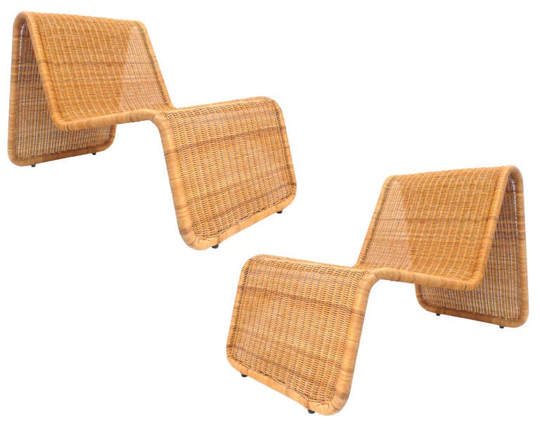 A wonderfully sculptural and unusual pair of Italian lounge chairs designed by Tito Agnoli in the 1960's and produced by Pierantonio Bonacina. Low, sleek and beautifully constructed of woven wicker over a steel frame. These interesting chairs can be