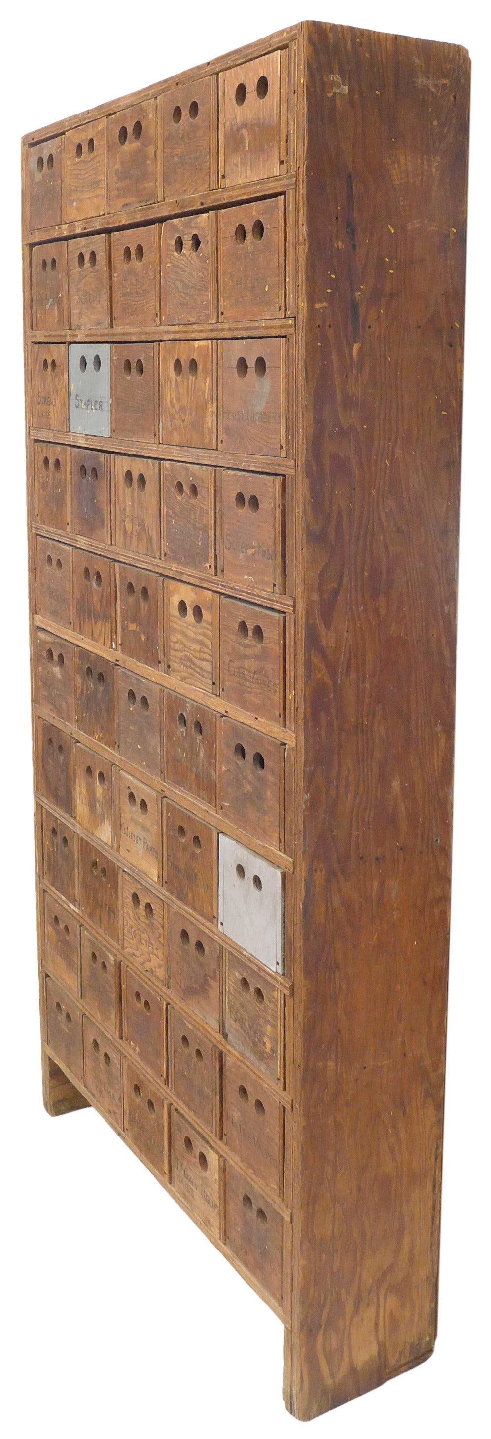 An incredible 50-drawer primitive cabinet in plywood.  A much desired, even patina from years of use with subtle remnants of paint throughout.  Drawer-fronts featuring handwritten labeling and double perforations for pulls.  An unintentionally but