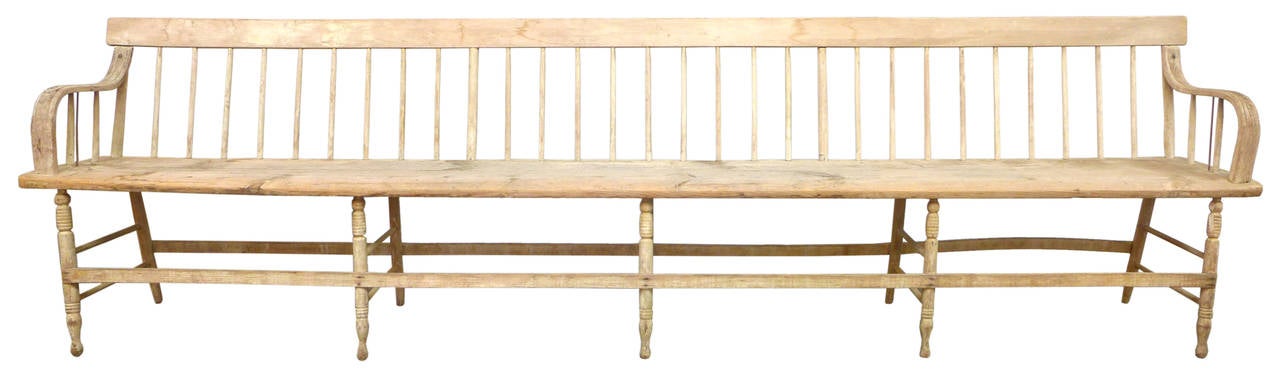 Monumental in scale (10 feet long), this exceptional spindle-back bench is both commanding and elegant with its exaggerated form, perfectly distressed paint patina and subtle metal details. Originating from New England and dating back to the early