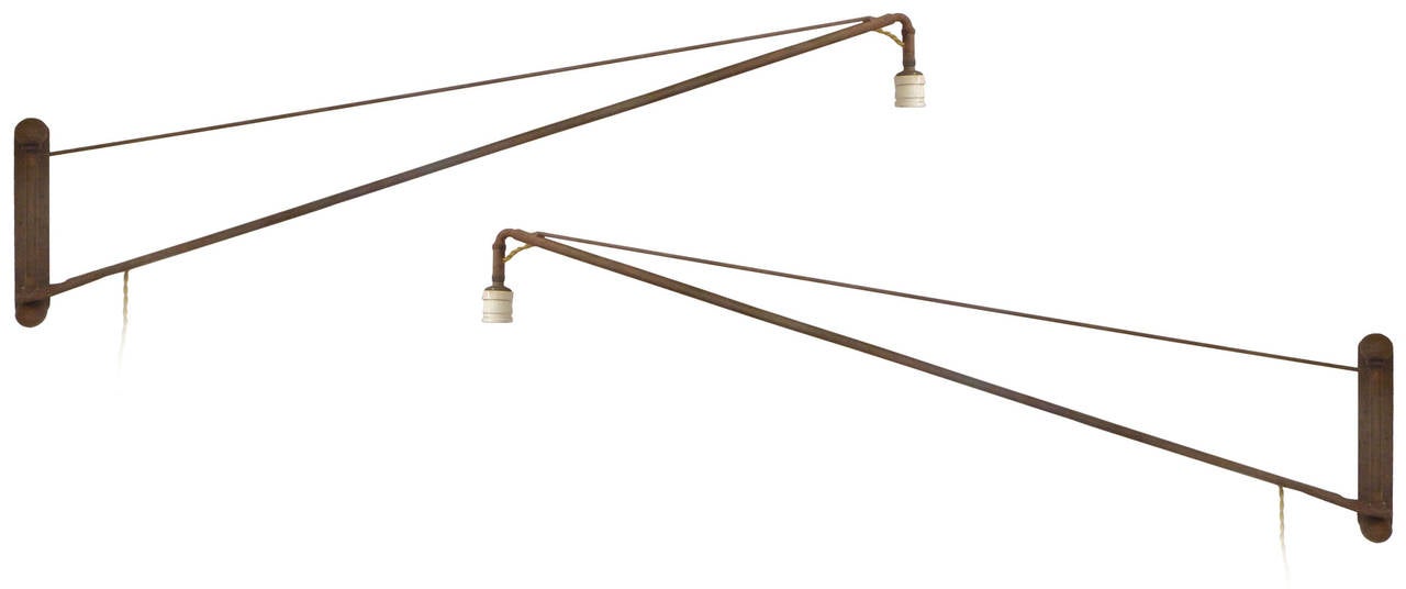 A wonderful pair of articulated long-arm sconces assembled from pieces of a Model T Ford.  Fusing folk art and industrial design, a precisely built pair of great scale producing beautifully slender silhouettes.  With arms able to swing freely