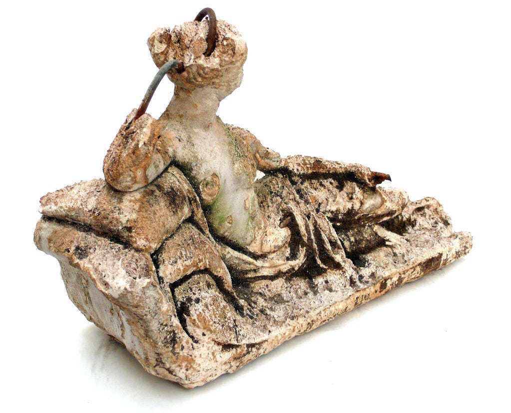 Concrete sculpture of a reclining female figure, seductively draped with a sheet. A wonderful example of turn of the century, figural garden statuary.The beautifully exposed armature and partial erosion from time add to the character of this piece.