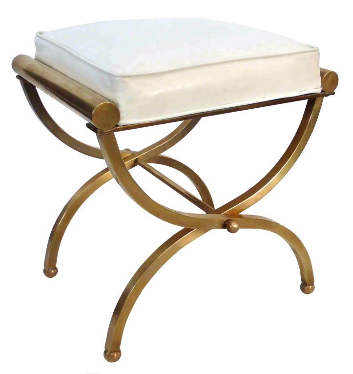 Elegant and sculptural brass stool with original white leatherette seat. An interesting, curvilinear X-frame form, sitting on machined brass ball feet. Beautifully constructed of square and tubular brass. A strong, decorative form.