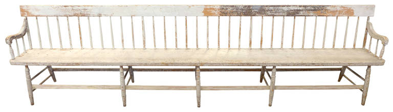 Monumental in scale (11 feet long), this exceptional spindle-back bench is both commanding and elegant with its exaggerated form and perfectly distressed paint patina. Originating from a turn of the century Maine factory waiting room, this piece