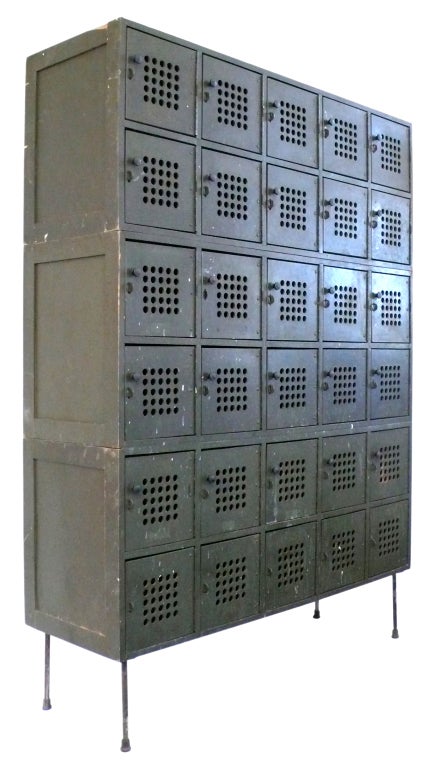 This graphic and utilitarian industrial locker/storage cabinet is made of wood and perforated masonite door panels and sits on it's original steel legs. It is composed of three, stacking bays of lockers (each bay is two rows high by five