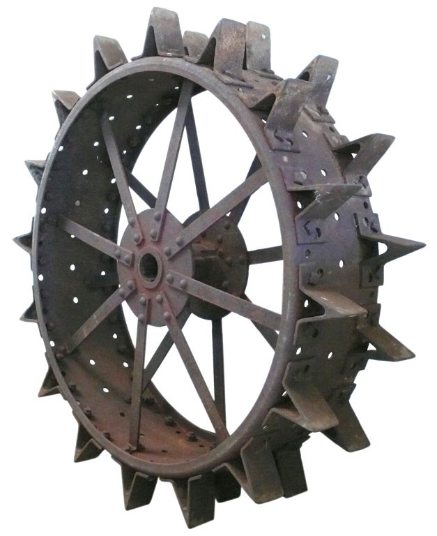 This huge and fantastic wheel came off of a 19th century farm tractor.  It has incredible scale, form and remnants of old red paint which adds beautifully to the rusted steel patina. An exceptional decorative object with unrivaled presence.