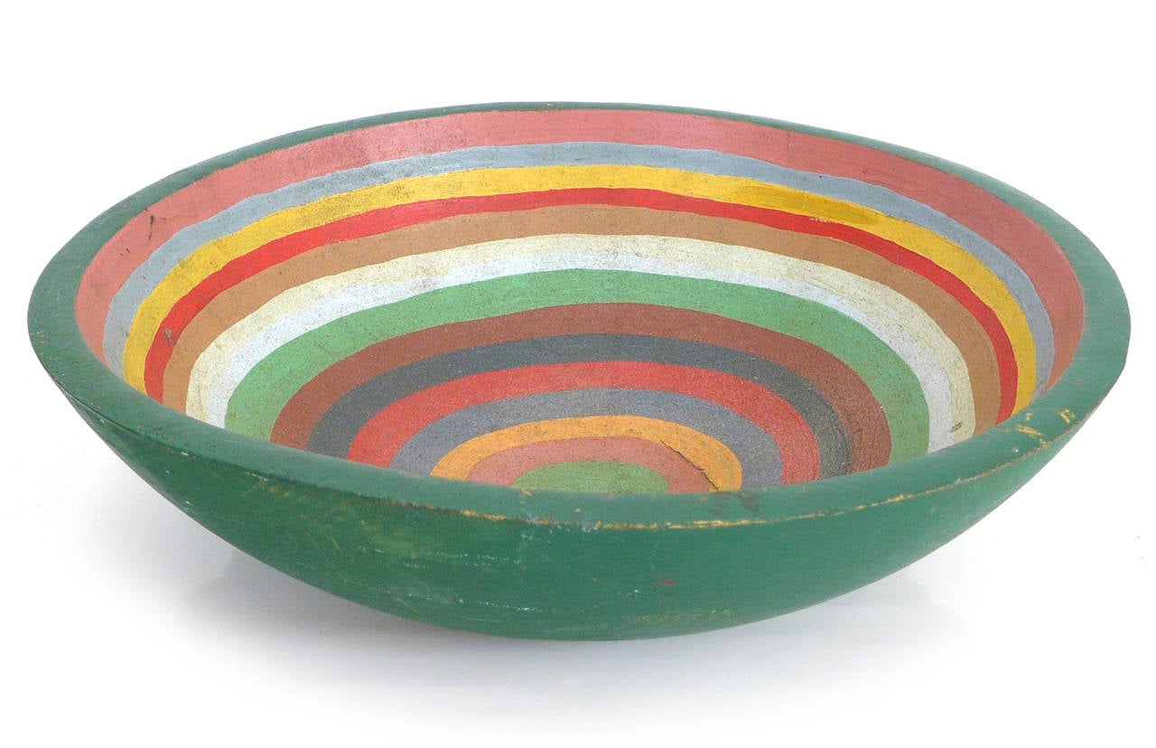 A beautifully hand-painted, hand-carved wood bowl wearing a lovely array of multicolored, concentric circles.  Much desired weathering and patina from years of use.