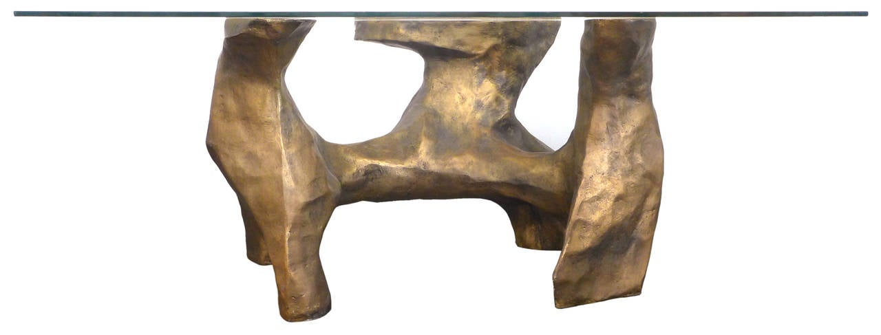 A fantastic, faux bronze, glass top table. A striking, highly-stylized, naturalistic form of cast fiberglass with a beautiful, applied faux-bronze patina, bearing a large, rectangular glass top. A dramatic and powerful, masculine table that could be