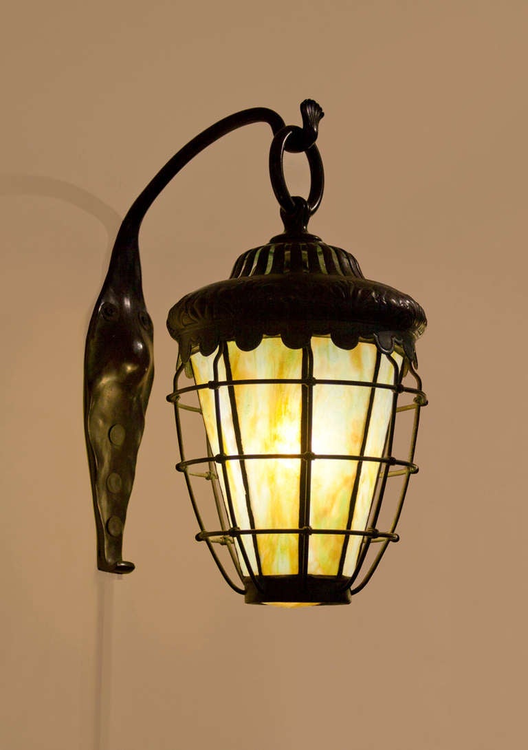 This lantern is one of a pair of Tiffany Studios lanterns which were a special commission for a home in eastern Pennsylvania, possibly unique.  Each lantern comprises a decorated and reticulated bronze bonnet with a fitted and 8-sided conical shade